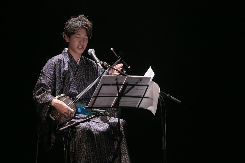 舞台で歌三線を演奏する様子